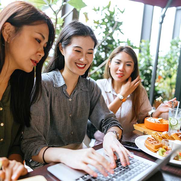 Three women using laptop at restaurant